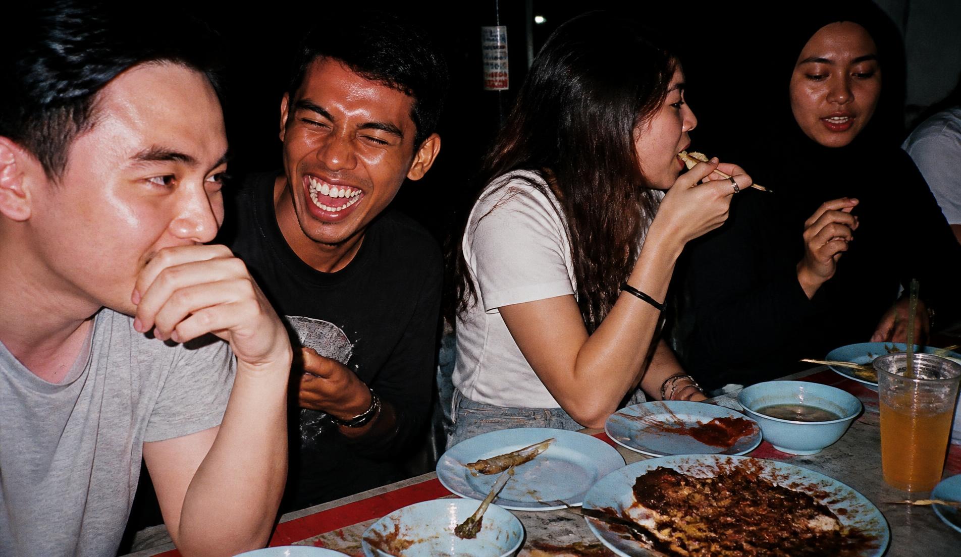 Warm Malaysian night market scene with local food stalls and customers